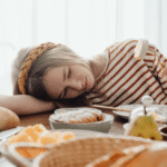 Exhausted girl resting head on breakfast table morning school sleep deprivation