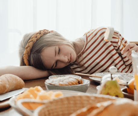 Exhausted girl resting head on breakfast table morning school sleep deprivation